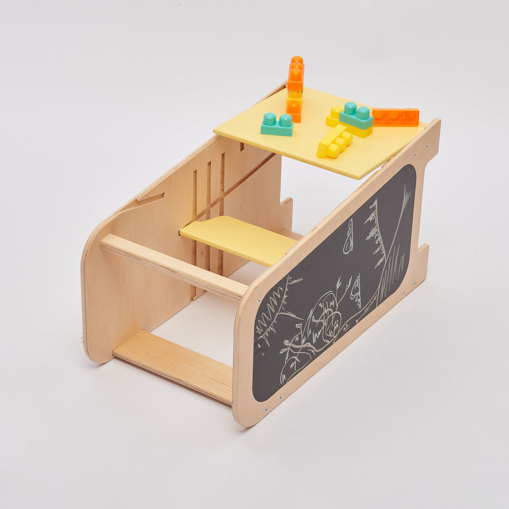 Montessori Lernturm aus Naturholz mit gelbem seitlichem Busy Board, ausgestattet mit interaktiven Zahnrädern, Schiebereglern und verschließbaren Elementen für Kleinkinder.